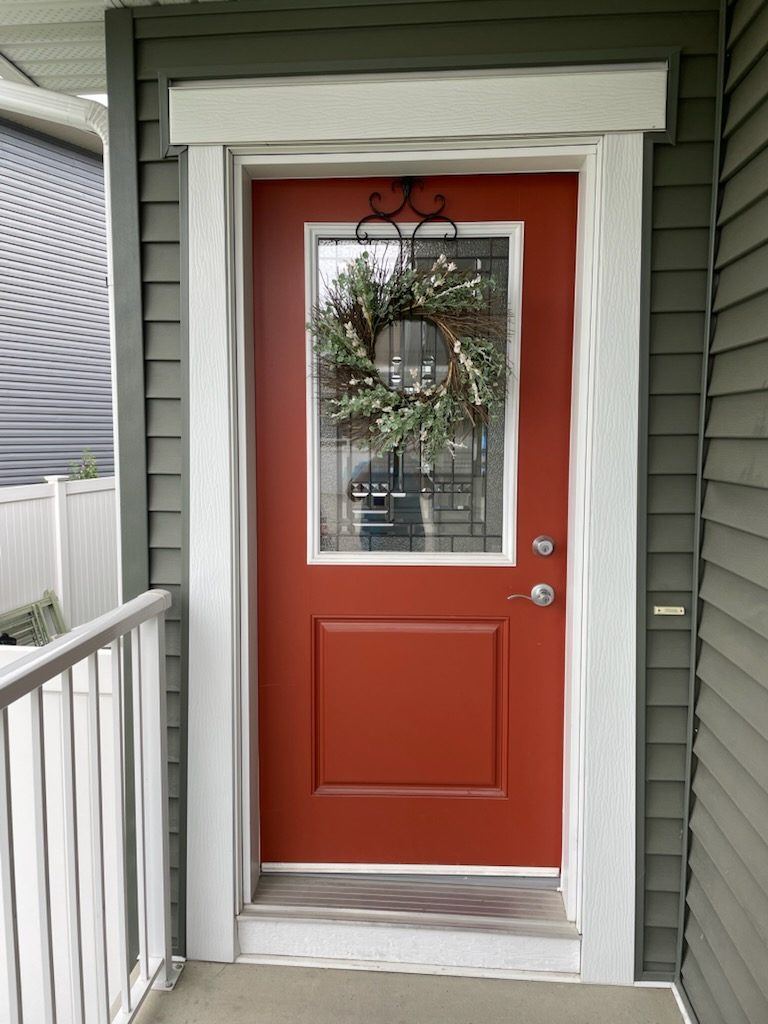 Red entry door with decorative glass before storm door installation in Calgary